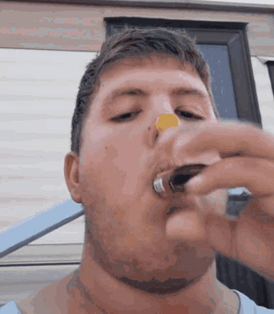 a man with a bottle cap on his nose is drinking from a glass