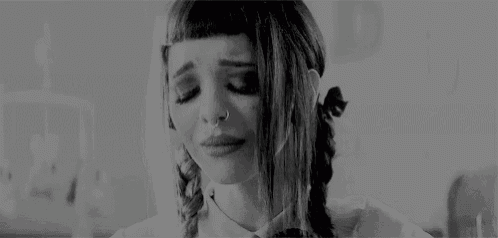 a black and white photo of a woman crying with a nose ring .