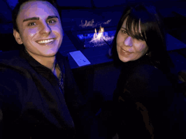 a man and a woman are posing for a picture in front of a building with lights on it