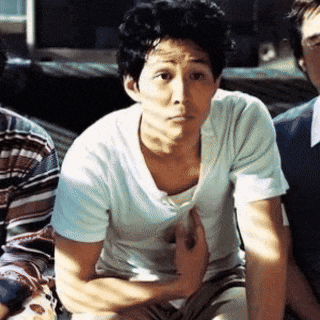 a man in a white t-shirt is sitting with his hands on his knees