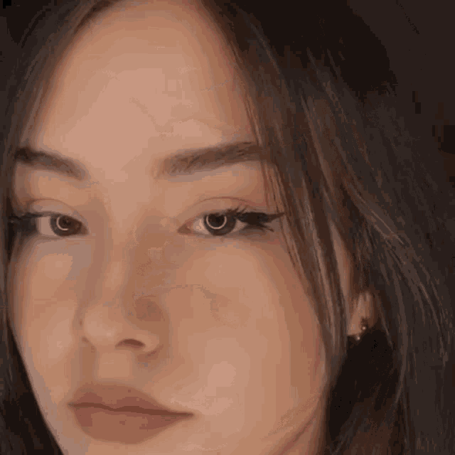 a close up of a woman 's face with long black hair and earrings .