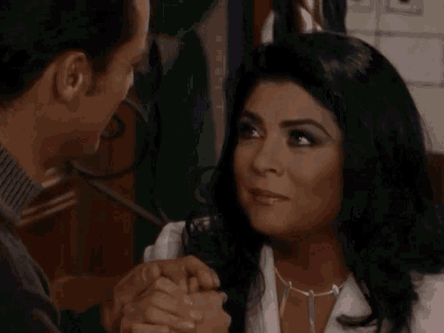 a man and a woman holding hands and looking at each other