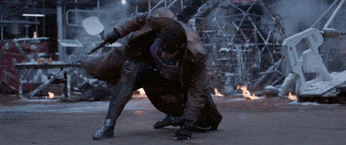 a man in a trench coat is kneeling down and holding a sword