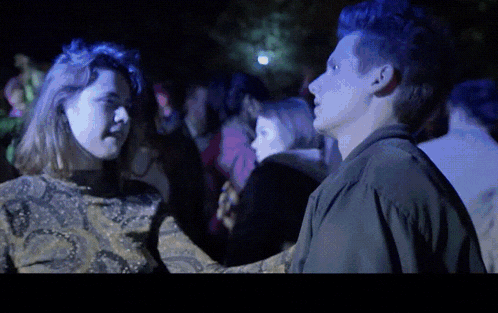 a man and a woman are looking at each other in a crowd