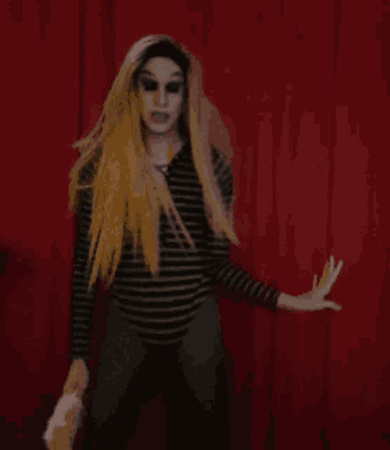 a woman in a striped shirt is standing in front of a red curtain