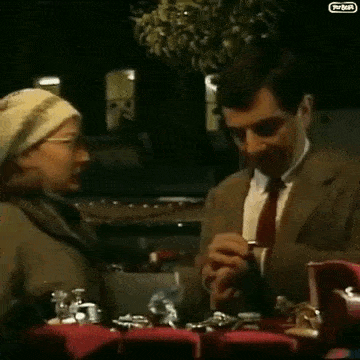 a man in a suit and tie is covering a woman 's mouth with his hand .