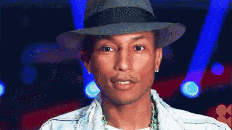 a man wearing a hat and a denim jacket looks at the camera
