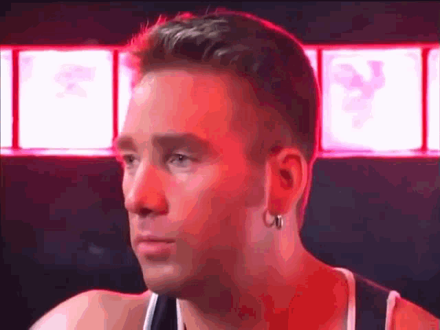 a man with a piercing in his ear is looking at the camera in a dark room .