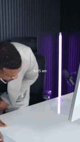 a man sitting at a desk with the time 9:05 am on the screen