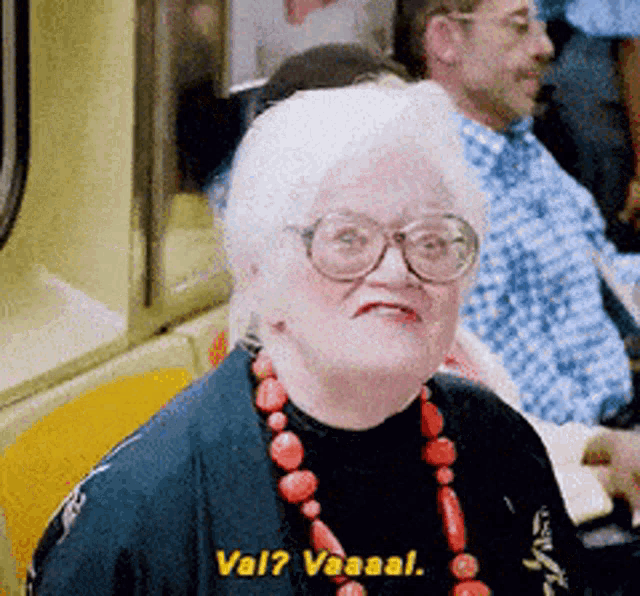 an elderly woman wearing glasses and a red necklace says val ? vaaal