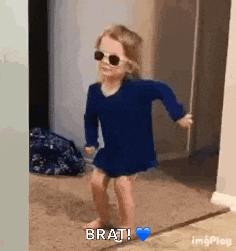 a little girl is wearing sunglasses and dancing in a room .