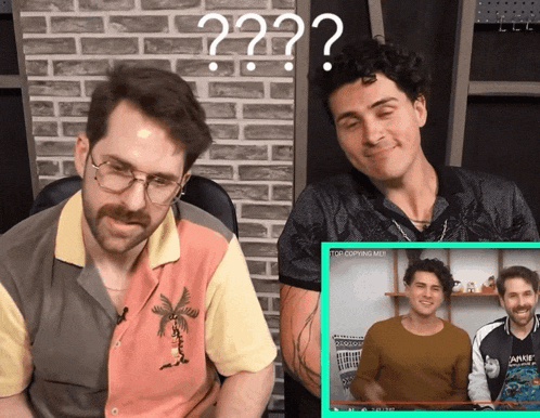 two men are sitting in front of a brick wall with a question mark above them