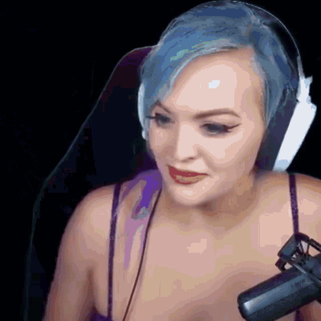 a woman with blue hair is sitting in front of a microphone wearing headphones
