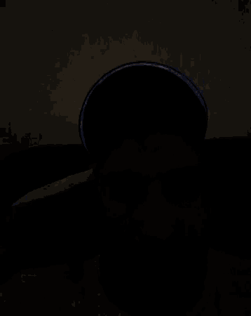 a man with a beard is wearing a hat that is reflective in the dark