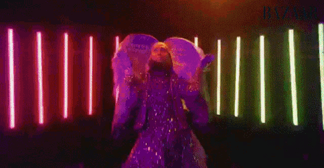 a man in a green costume is dancing in a dark room with green lights behind him .
