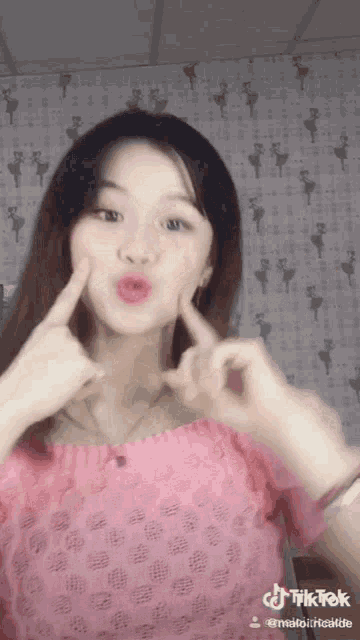 a girl in a pink top is making a funny face and has tiktok written on the bottom right
