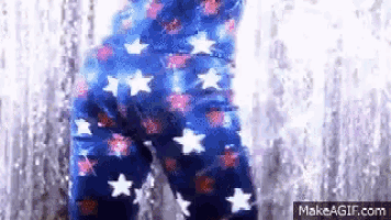 a person wearing a pair of blue pants with stars on them is standing in front of a waterfall .