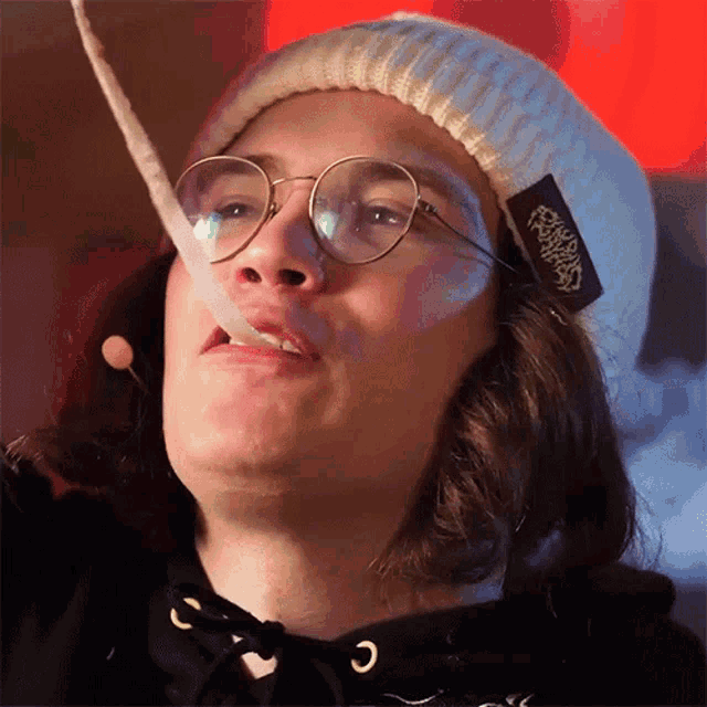 a man wearing glasses and a beanie has a tag on his hat that says ' a ' on it