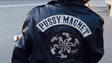 a person wearing a black leather jacket with a patch that says pussy magnet