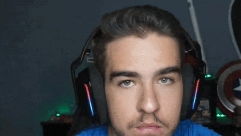 a man wearing headphones looks at the camera with a shield in the background