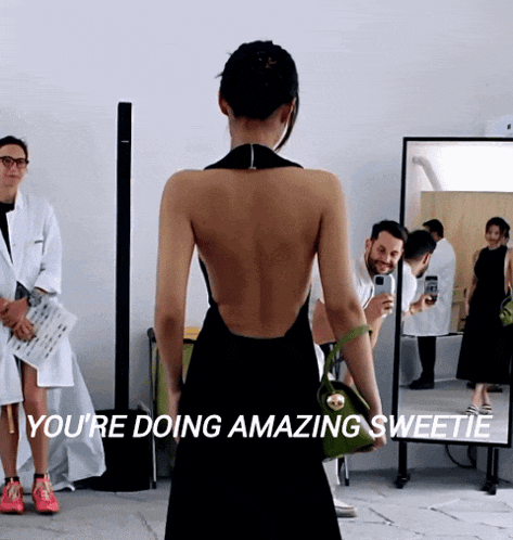 a woman in a black dress stands in front of a mirror with the words " you 're doing amazing sweetie "