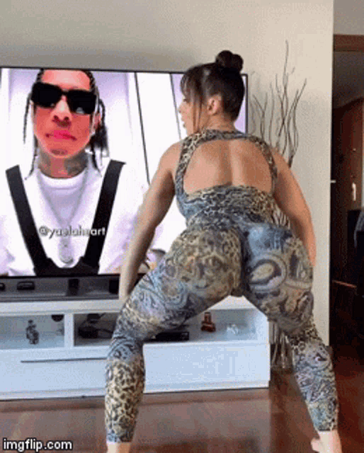 a woman is dancing in front of a tv with a picture of a man on it ..