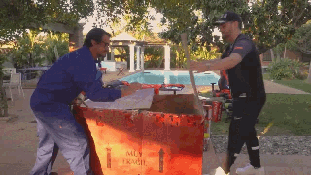 two men carrying a box that says muy fragile