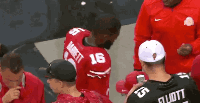 a man in a red number 16 jersey talks to another man in a black number 15 jersey