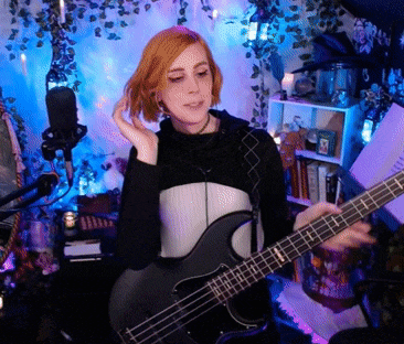 a woman is playing a bass guitar in a room