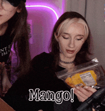 a woman is holding a bag of mango chips in her hands