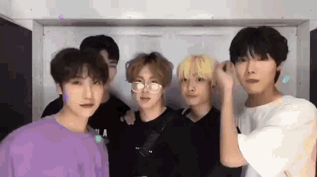 a group of young men are standing next to each other in a room and posing for a picture .