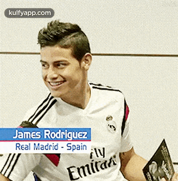 james rodriguez from real madrid spain is smiling and holding a book .