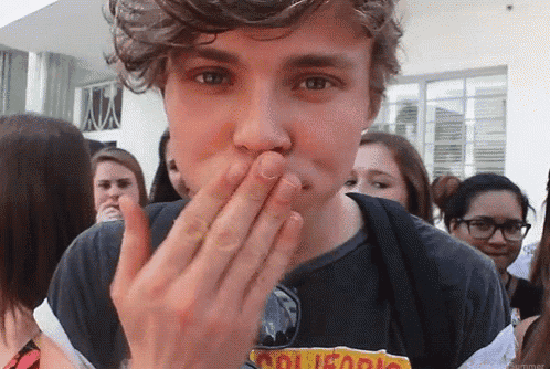 a young man wearing a shirt that says california covers his mouth with his hand