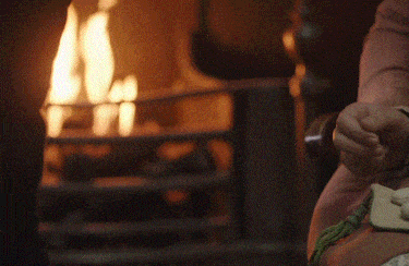 a person is sitting in front of a fireplace holding a candle