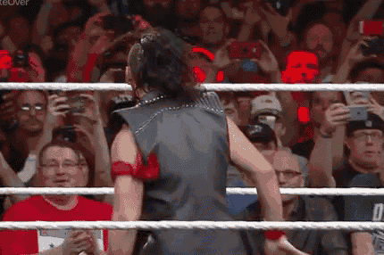 a man is standing in a wrestling ring in front of a crowd of people .