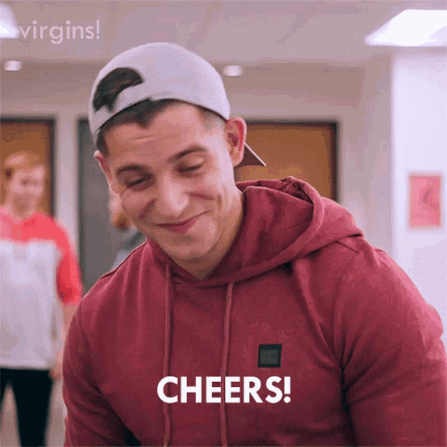 a man wearing a red hoodie and a white baseball cap says cheers