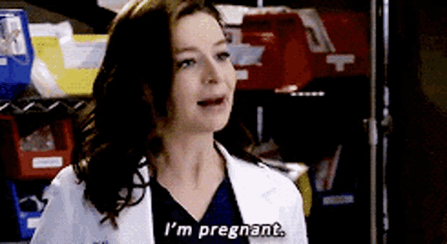 a woman in a lab coat is saying i 'm pregnant .