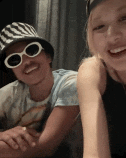a man wearing a striped hat and sunglasses is smiling next to a woman
