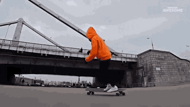 a person in an orange hoodie is riding a skateboard under a bridge that says awesome