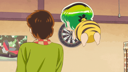 a man in a green shirt stands in front of a dart board with a green and yellow character on it
