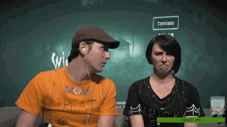a man and a woman are sitting in front of a screen that says " continue "