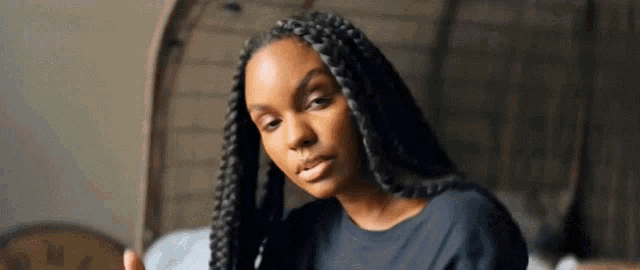 a woman with braids in her hair is sitting in a chair looking at the camera .