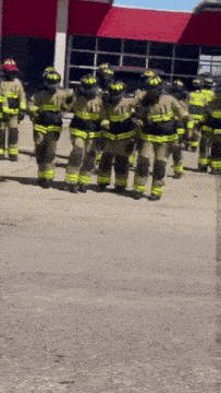 a group of firefighters are standing in front of a building