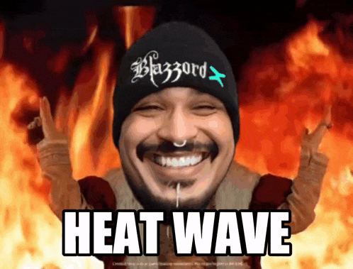 a man wearing a beanie that says blazzard is smiling in front of flames