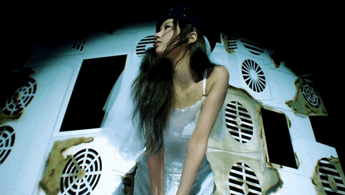 a woman in a white dress is standing in front of a wall of holes in it