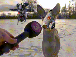 a person is holding a microphone in front of a deer with a fish in its mouth