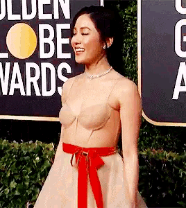 a woman is standing in front of a sign that says golden globes