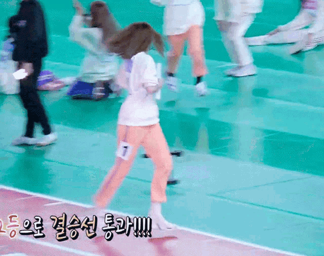 a girl wearing a number 1 on her pants is walking on a track