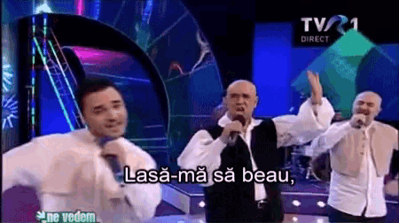 a group of men singing in front of a tv screen