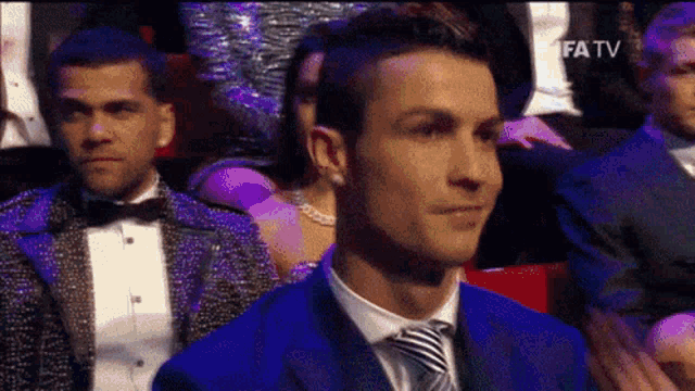 a man in a blue suit and tie is sitting in front of a screen that says fifa tv on it